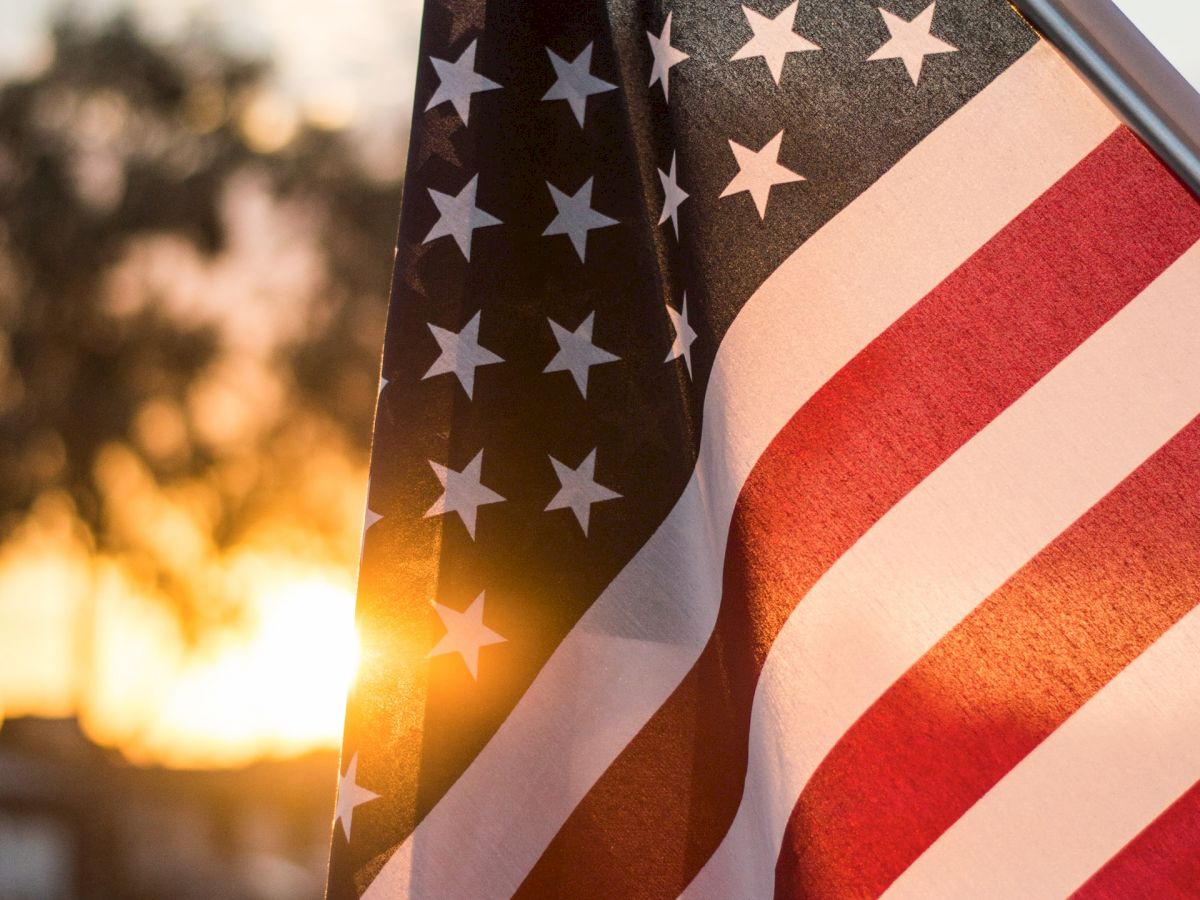 An American flag is displayed prominently with the sun setting in the background, casting a warm glow on the scene.