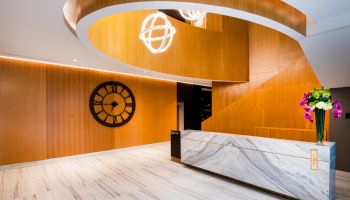 A modern lobby with a wooden spiral staircase, marble reception desk, large wall clock, and contemporary light fixtures ends the sentence.